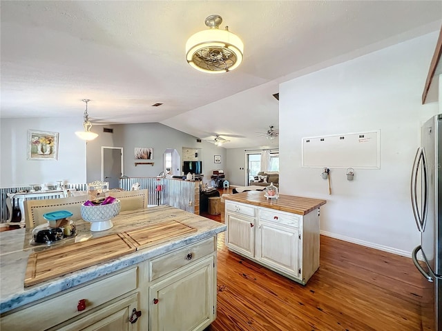 kitchen featuring hanging light fixtures, vaulted ceiling, light hardwood / wood-style flooring, ceiling fan, and stainless steel refrigerator