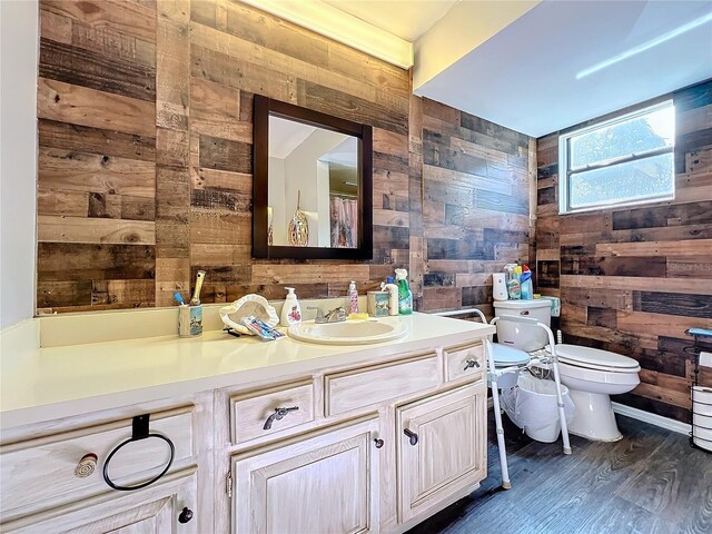 bathroom featuring vanity, toilet, wood-type flooring, and wooden walls