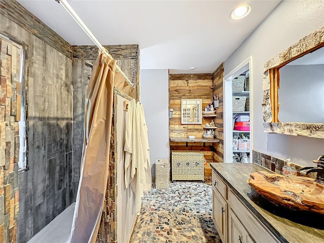 bathroom with a shower with curtain, vanity, and wooden walls