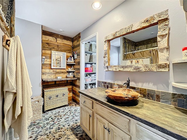 bathroom with a shower with shower curtain, vanity, and wooden walls