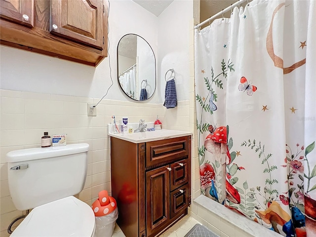 bathroom featuring vanity, toilet, walk in shower, and tile walls