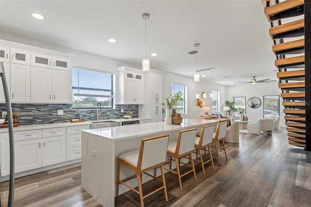 kitchen featuring ceiling fan, sink, a kitchen island, decorative light fixtures, and white cabinets