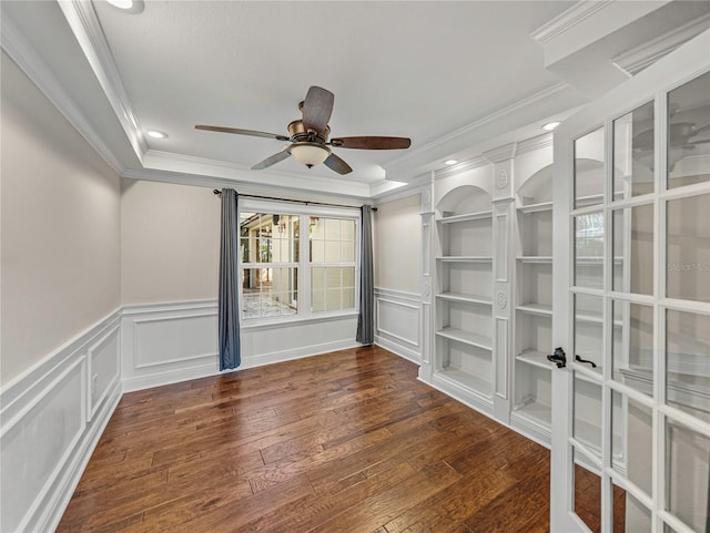 spare room with dark hardwood / wood-style flooring, ceiling fan, built in features, and crown molding