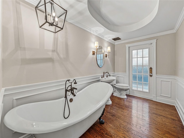 bathroom featuring a tub to relax in, a tray ceiling, crown molding, hardwood / wood-style flooring, and toilet