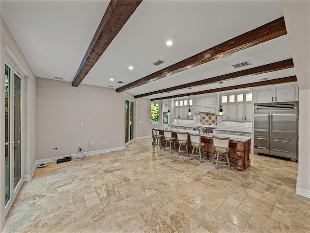 kitchen featuring stainless steel built in refrigerator, a breakfast bar, pendant lighting, beam ceiling, and a kitchen island