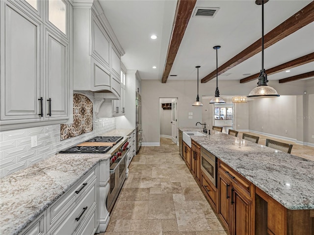 kitchen featuring pendant lighting, sink, built in appliances, beam ceiling, and white cabinetry