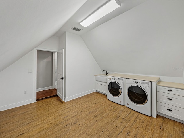 laundry room featuring cabinets, light wood-type flooring, separate washer and dryer, and sink