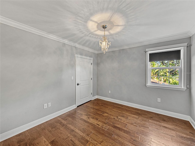 empty room featuring hardwood / wood-style floors, a notable chandelier, and crown molding