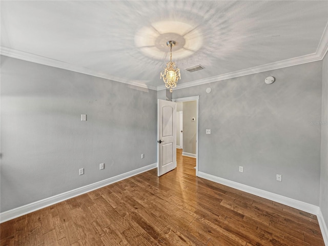 spare room with hardwood / wood-style flooring, ornamental molding, and a chandelier