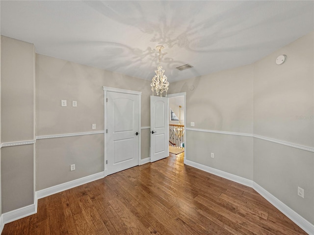 spare room featuring an inviting chandelier and hardwood / wood-style flooring