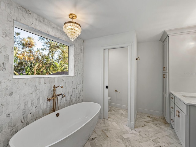 bathroom featuring toilet, vanity, a bath, and a notable chandelier