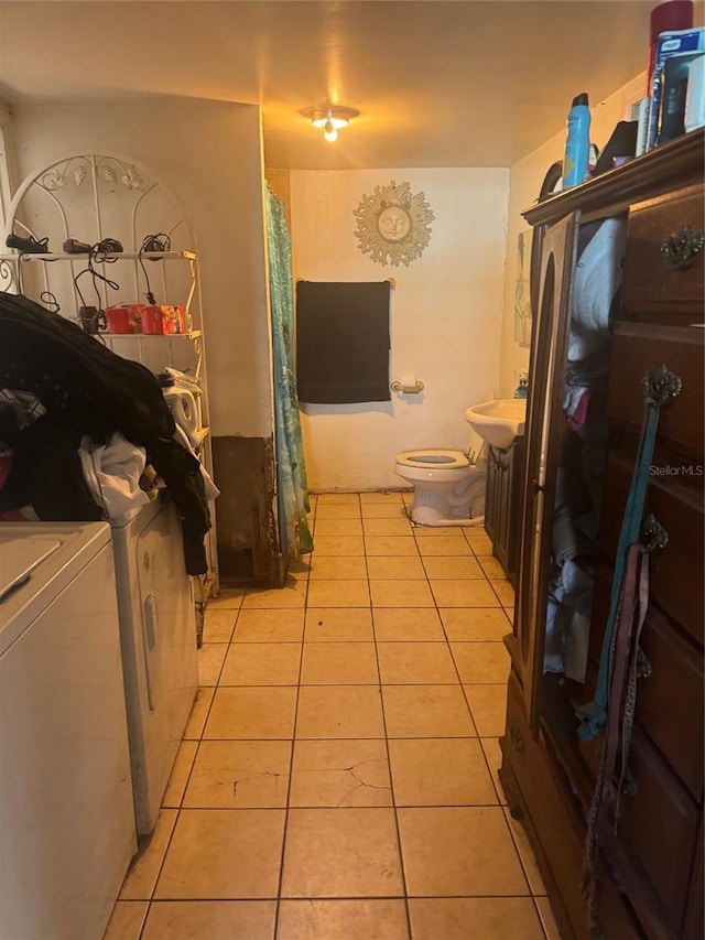 bathroom with toilet, tile patterned floors, washer and clothes dryer, and sink