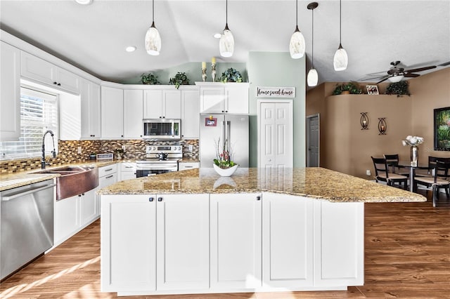 kitchen with stainless steel appliances, ceiling fan, sink, pendant lighting, and a kitchen island