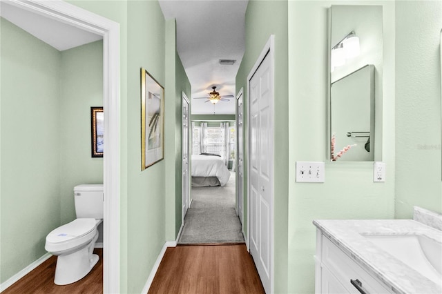 bathroom featuring vanity, hardwood / wood-style flooring, toilet, and ceiling fan