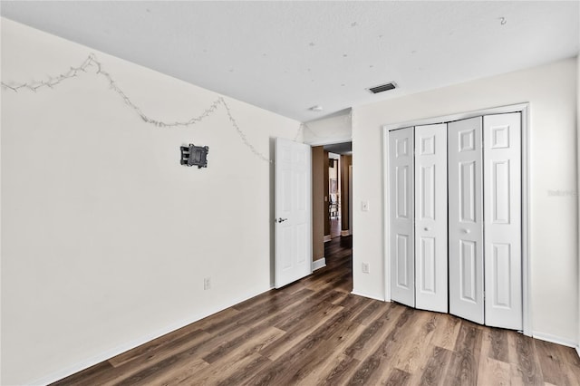 unfurnished bedroom with dark wood-type flooring and a closet