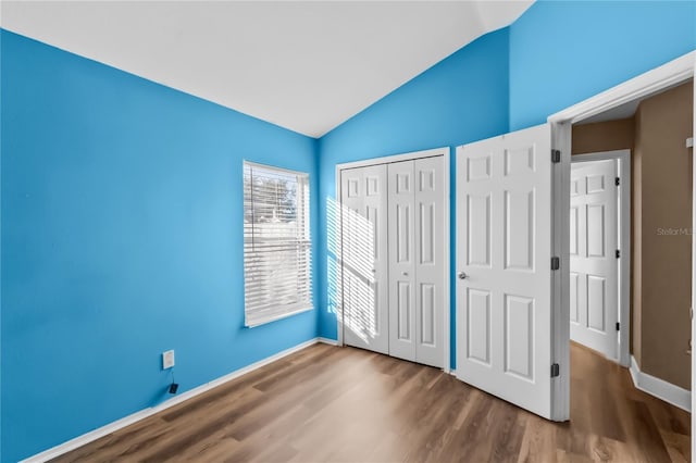 unfurnished bedroom featuring a closet, vaulted ceiling, and hardwood / wood-style flooring