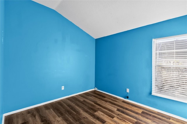 spare room with wood-type flooring and lofted ceiling