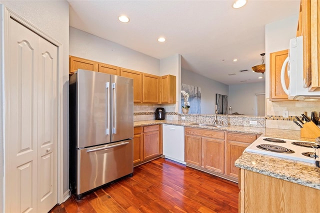 kitchen featuring kitchen peninsula, dark hardwood / wood-style flooring, backsplash, white appliances, and sink