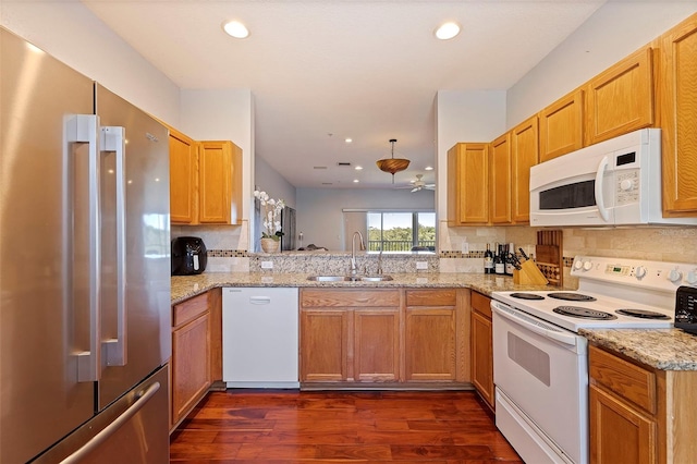 kitchen with kitchen peninsula, light stone countertops, white appliances, ceiling fan, and sink