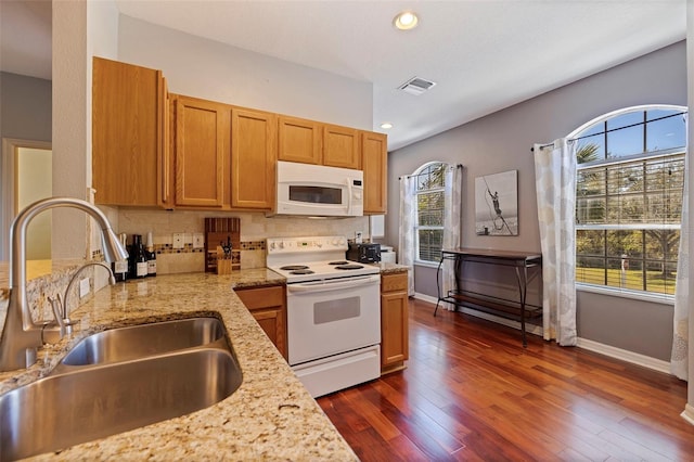 kitchen with backsplash, light stone counters, white appliances, dark wood-type flooring, and sink