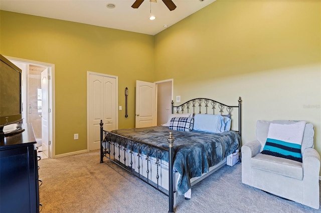 carpeted bedroom with ceiling fan, ensuite bathroom, and a high ceiling