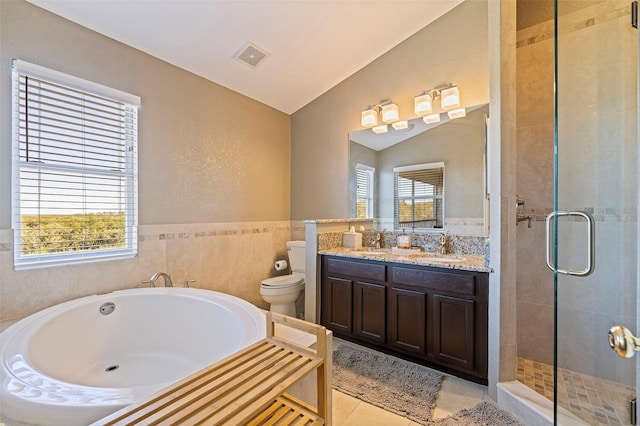 full bathroom featuring vaulted ceiling, tile walls, tile patterned flooring, shower with separate bathtub, and toilet