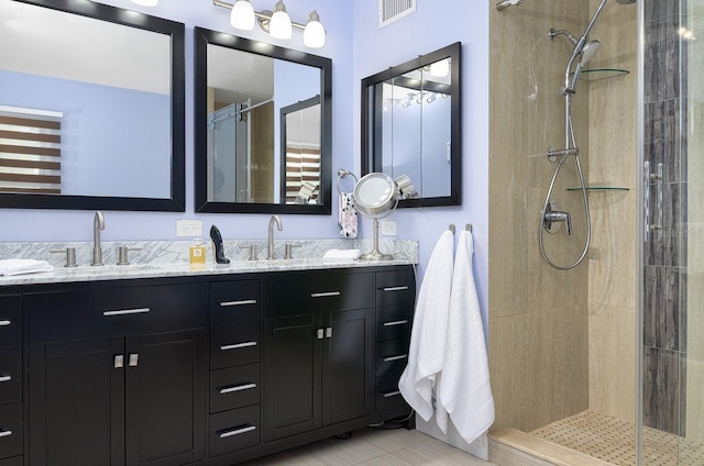 bathroom with tile patterned flooring, vanity, and tiled shower