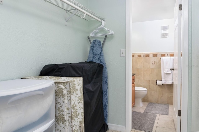 bathroom featuring toilet, vanity, tile patterned floors, and tile walls