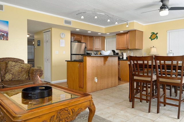 kitchen featuring crown molding, ceiling fan, stainless steel fridge, a textured ceiling, and kitchen peninsula