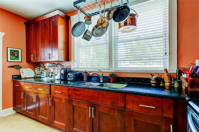 kitchen featuring dark stone countertops, stove, and sink