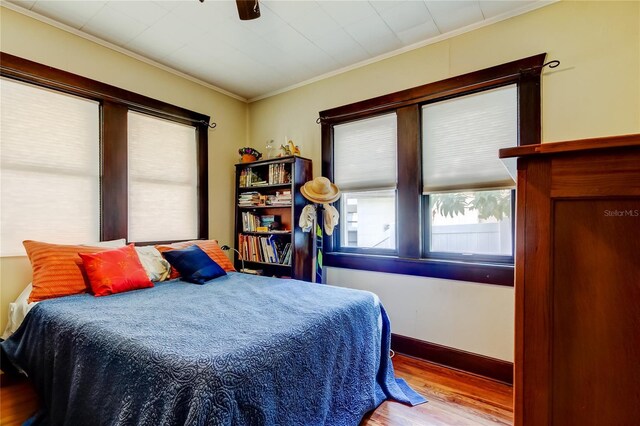 bedroom featuring ceiling fan, light hardwood / wood-style floors, and ornamental molding