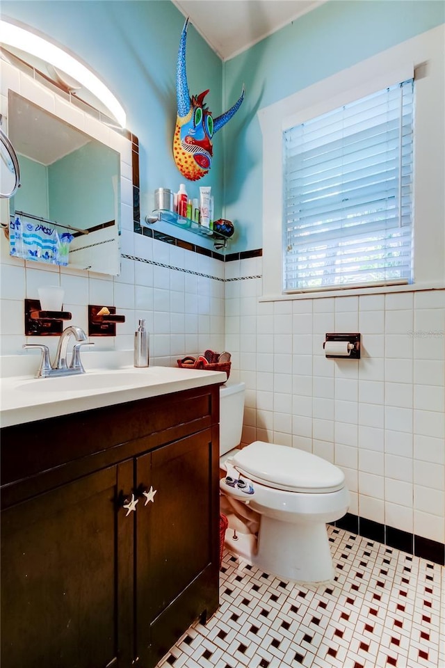 bathroom featuring tile patterned flooring, vanity, toilet, and tile walls