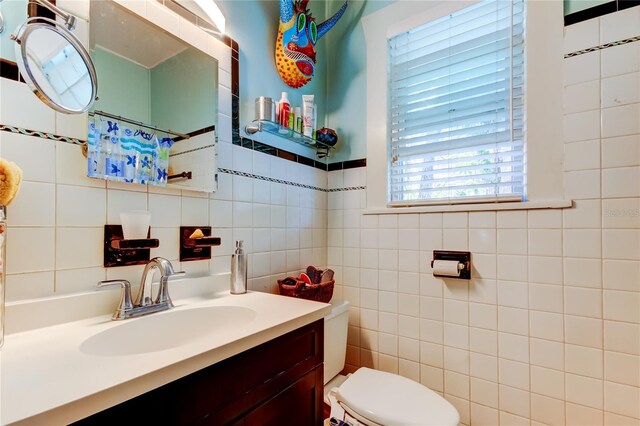 bathroom with vanity, tile walls, and toilet