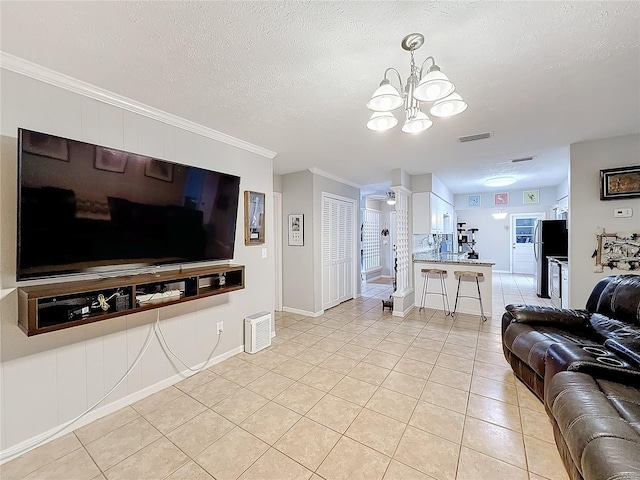 living room with light tile patterned floors, a textured ceiling, ornamental molding, and a notable chandelier