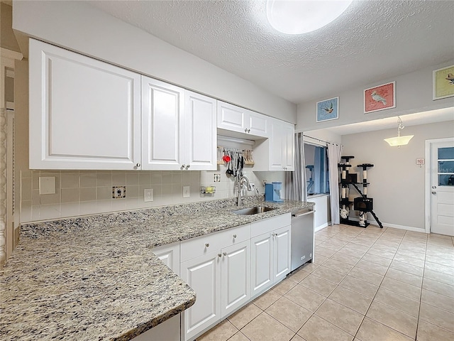 kitchen with stainless steel dishwasher, a textured ceiling, sink, white cabinetry, and light tile patterned flooring