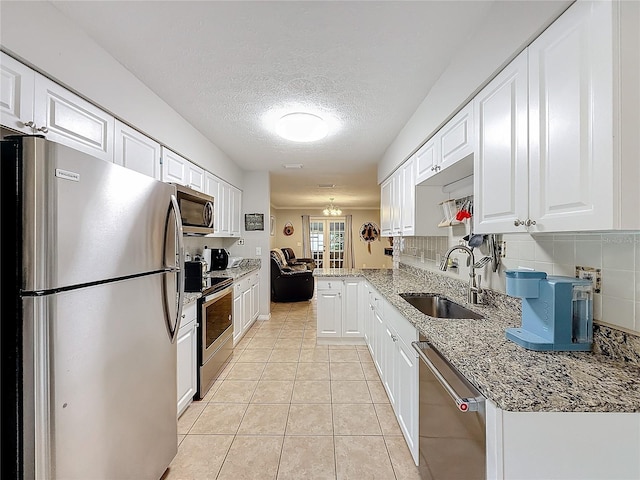 kitchen with light stone countertops, sink, white cabinets, and stainless steel appliances