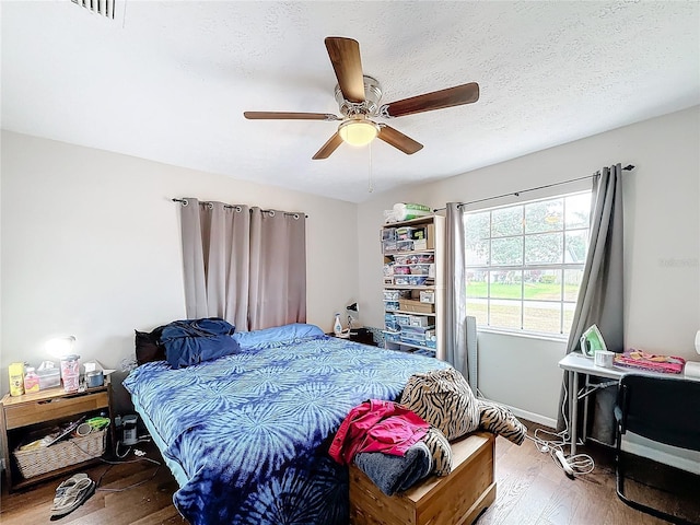 bedroom featuring ceiling fan, hardwood / wood-style floors, and a textured ceiling