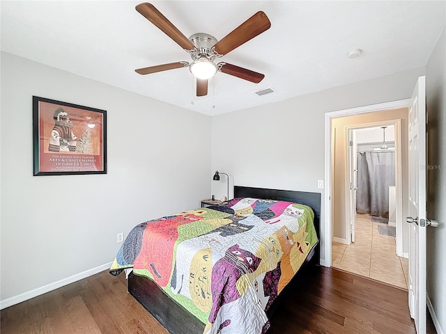 bedroom with a walk in closet, a closet, hardwood / wood-style flooring, and ceiling fan