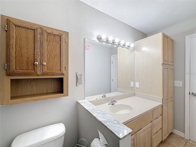 bathroom featuring tile patterned flooring, vanity, a textured ceiling, and toilet