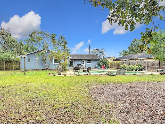 rear view of property featuring a fenced in pool, a patio area, and a yard