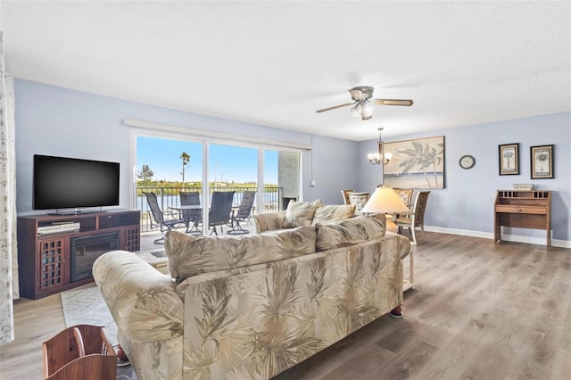 living room with a textured ceiling, light hardwood / wood-style flooring, and ceiling fan with notable chandelier