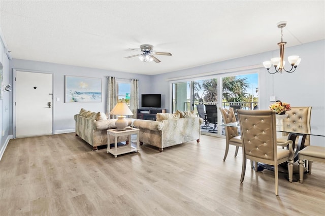 living room with a textured ceiling, ceiling fan with notable chandelier, and light hardwood / wood-style flooring