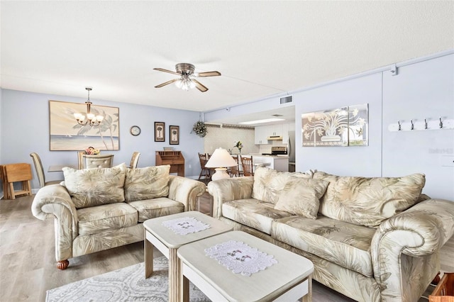 living room featuring a textured ceiling, ceiling fan with notable chandelier, and hardwood / wood-style flooring