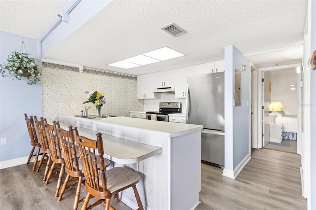 kitchen with kitchen peninsula, stainless steel appliances, white cabinetry, and a breakfast bar area