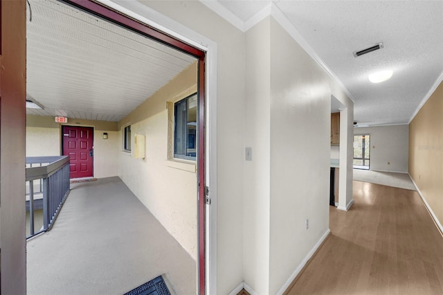 hallway featuring hardwood / wood-style flooring, crown molding, and a textured ceiling