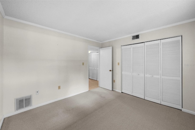 unfurnished bedroom with ornamental molding, light colored carpet, a textured ceiling, and a closet