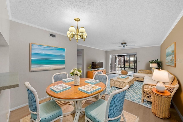 dining space with a textured ceiling, ceiling fan with notable chandelier, light hardwood / wood-style floors, and ornamental molding