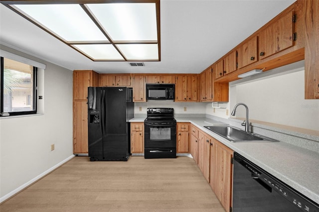 kitchen with sink, light hardwood / wood-style floors, and black appliances