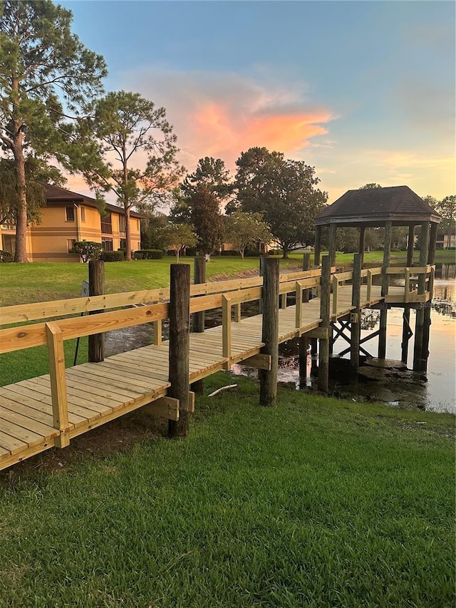 view of dock with a water view, a gazebo, and a lawn