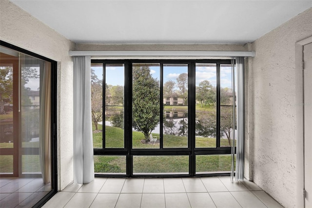 doorway to outside with a water view and light tile patterned floors